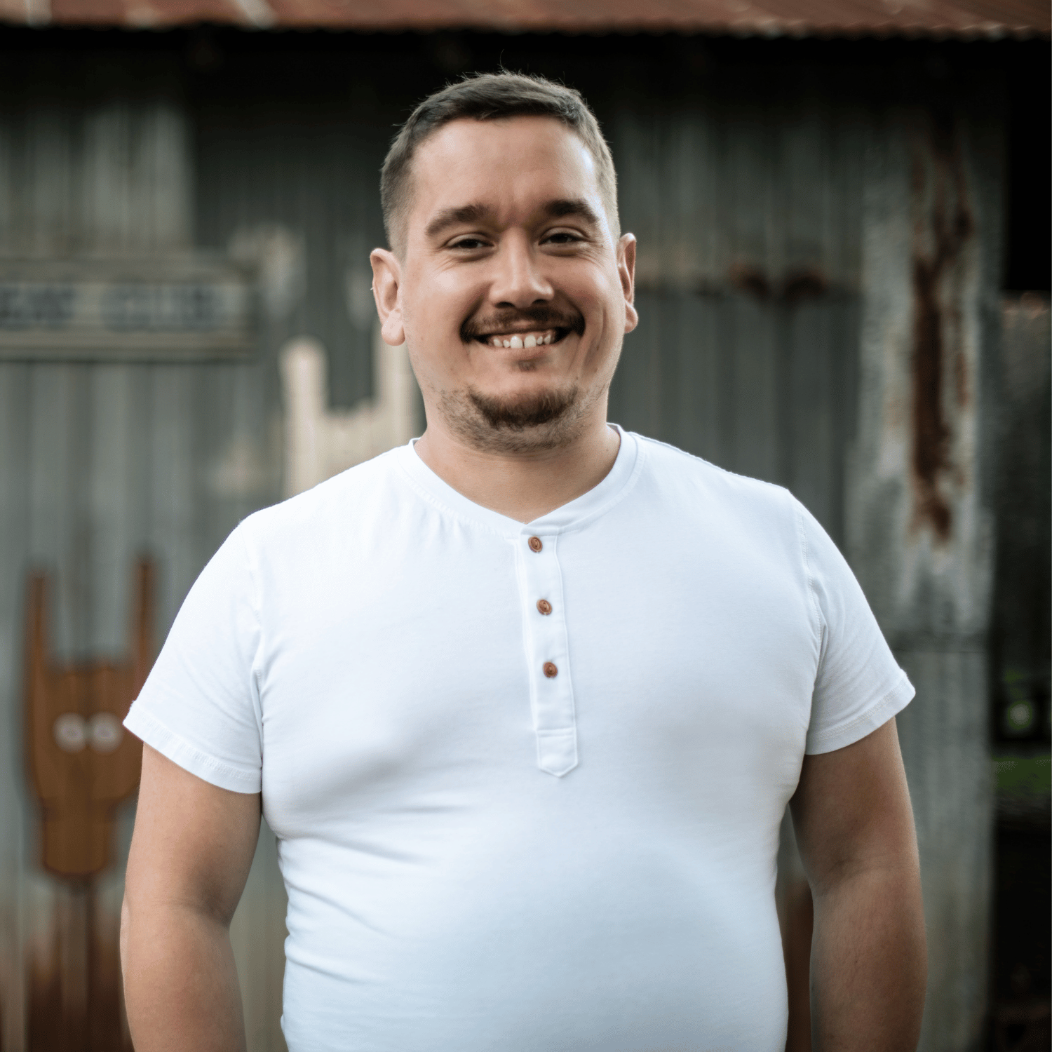 TJ, founder of Twist Web Studio, smiling outdoors in a white henley shirt